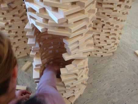 Foto: Schülerin baut an einer Archikulptur aus Holzbauklötzen